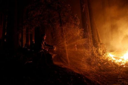 Cal Fire firefighter Anthony Quiroz douses water on a flame as he defends a home during the CZU Lightning Complex Fire in Boulder Creek, California, U.S. August 21, 2020. REUTERS/Stephen Lam