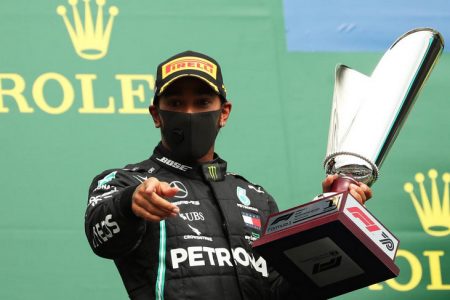 Mercedes’ Lewis Hamilton celebrates with the trophy on the podium after winning the race yesterday. Pool via REUTERS/Francisco Seco.