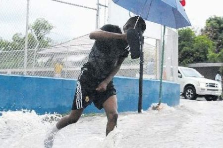 This man makes his way through gushing water on Maxfield Avenue in St Andrew yesterday as parts of the island were drenched by showers associated with Tropical Storm Laura. (Photo: Garfield Robinson)