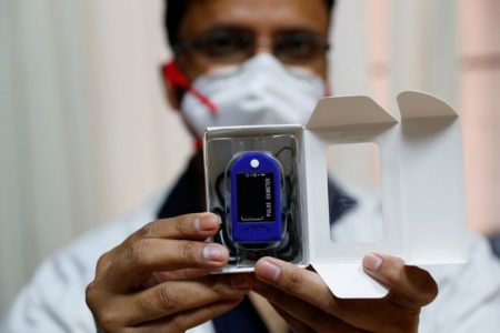 A health worker shows a pulse oximeter before delivering it to a patient infected with the coronavirus disease in New Delhi, India, August 26, 2020. REUTERS/Adnan Abid