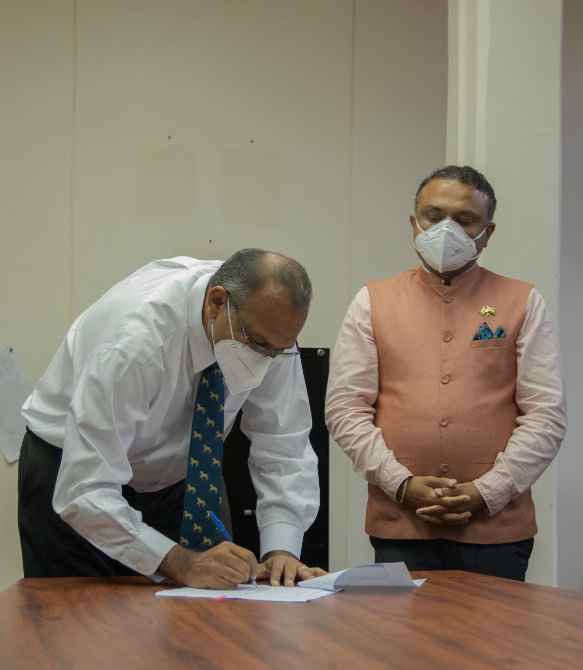 Minister of Health Dr Frank Anthony signing the agreement for the Indian assistance as High Commissioner of India,  Dr K J Srinivasa watches on (Ministry of Public Health photo)