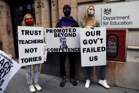 Students wearing protective face masks hold placards as they protest outside the department of education, amid the spread of the coronavirus disease (COVID-19), in London, Britain, August 15, 2020. REUTERS/Simon Dawson