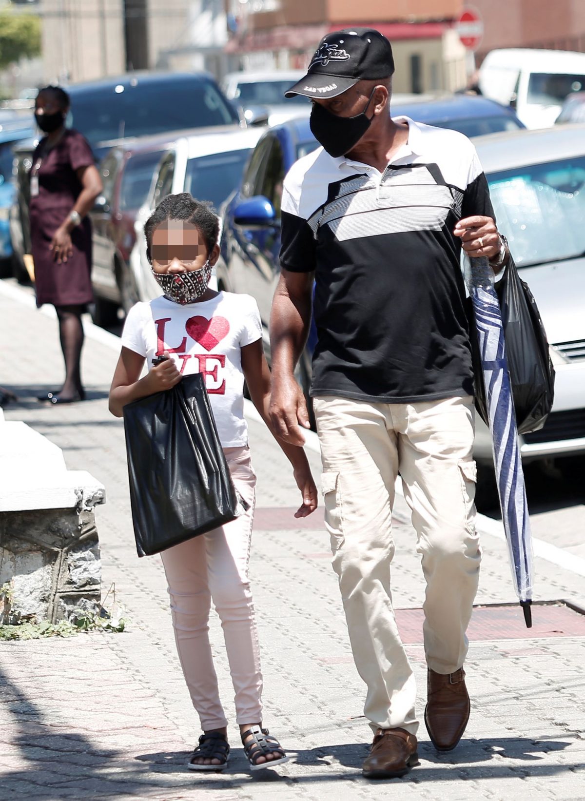 A child and man wearing masks to help prevent the spread of COVID-19 walk along Independence Square, Port-of-Spain, yesterday.