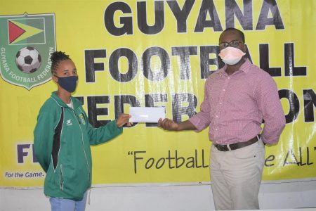 GFF President Wayne Forde (right) presents the financial assistance to footballer Shennel Daniels
