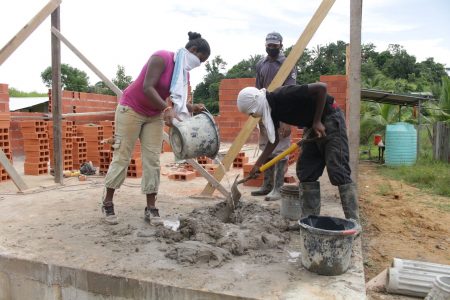 SEA student Ravi Boodram and his sister Meera Boodram helps carpenter Brandon Peterson with building a home at Wilson Road, Penal.