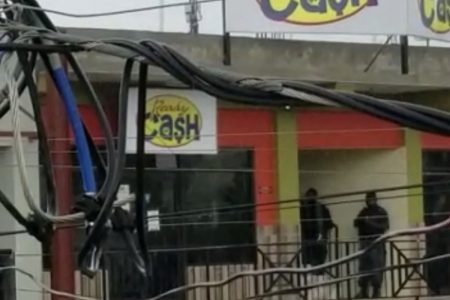 A screenshot from a video showing police personnel (right) outside a Ready Cash outlet in Junction, St Elizabeth where a robbery is under way.

