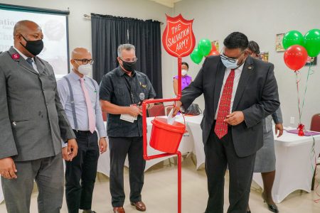 President Irfaan Ali makes a deposit into one of the Salvation Army’s Kettle at the launching of the annual Christmas Kettle Appeal at Duke Lodge on Friday (Office of the President photo)
