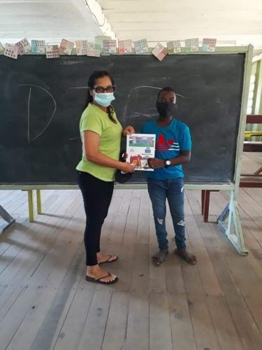 A student receives his package from his teacher at the Enmore Primary School, on the East Coast of Demerara (DPI photo) 