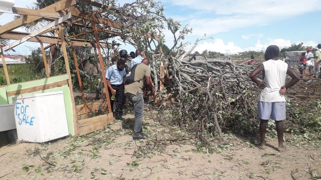 Police and residents inspecting the scene after a tree fell and injured several persons residing on a dam at Success (Guyana Police Force photo)