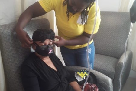 A member of the “Girls Inspire Girls” team affixing a mask to one of the patients. The patient is also wearing one of the donated turbans. 