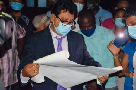 Attorney General Anil Nandlall examining the transport produced by Abdool Azim. (Department of Public Information photo)
