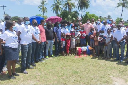  Minister of Culture, Youth and Sport, Charles Ramson Jr., (pink), presents the sports equipment to the residents of the Agricola community in the presence of Assistant Police Commissioner Clifton Hickens and other members of the ministry.