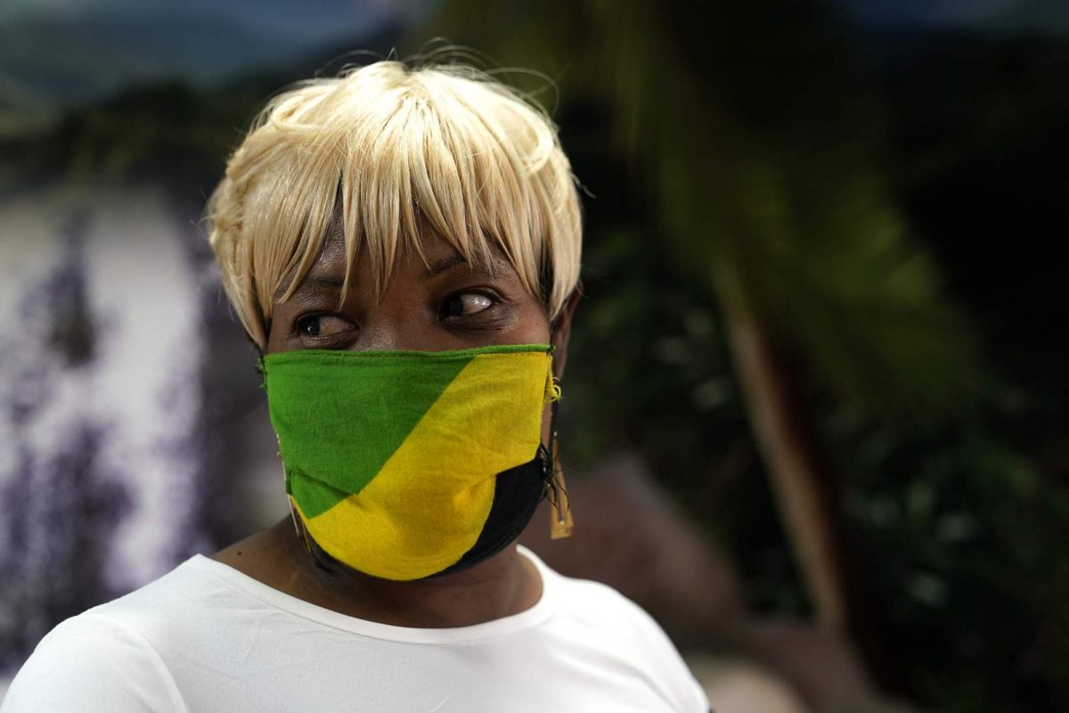 n this Aug. 26, 2020, photo Sophia Ball wears a protective face covering in the colors of the Jamaican flag as she picks up her order at the Dutch Pot Jamaican Restaurant in Pembroke Pines, Fla. (AP Photo/Lynne Sladky)