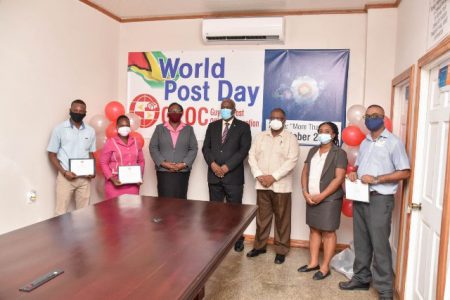 Prime Minister Mark Phillips (centre) posing with post office staff on World Post Day