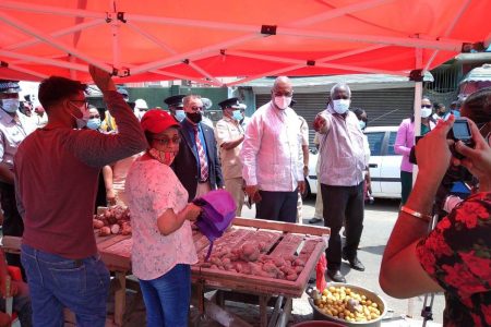 Minister of Home Affairs Robeson Benn (pointing) warns two vendors that they are not supposed to be plying their trade at the location where they currently operate. (Ministry of Public Works photo)