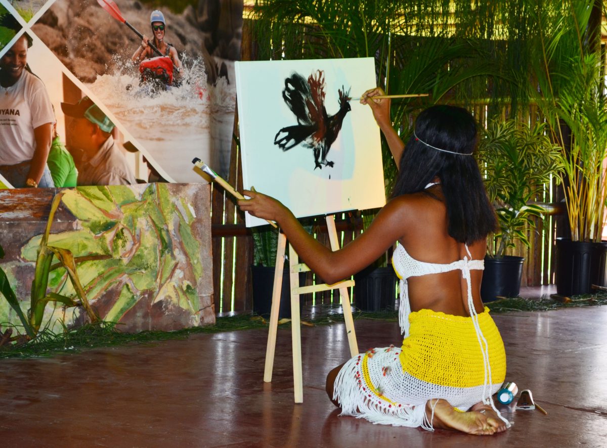 An artist out of Moraikobai, painting the Canje Pheasant as she tells the mythical story of its origin