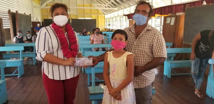 Minister of Education Priya Manickchand handing over a voucher to a parent during yesterday’s distribution exercise. Select parents yesterday received vouchers, which are due to be distributed by head teachers across Region Six from this week.
