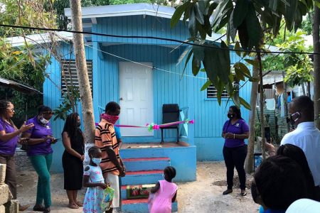 Franklyn Bodden and his two daughters, in the company of personnel from the Social Development Commission and the Runaway Bay Community Development Council, stand in front the new house he was gifted.
