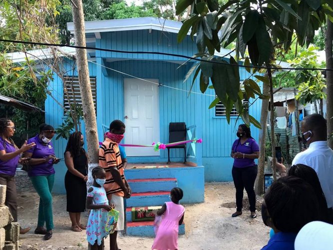 Franklyn Bodden and his two daughters, in the company of personnel from the Social Development Commission and the Runaway Bay Community Development Council, stand in front the new house he was gifted.
