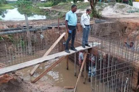 Region Two Vice-Chairman Humace Oudit (right) and the Overseer viewing the construction of the concrete culvert across the Lima Sands Road. (DPI photo)