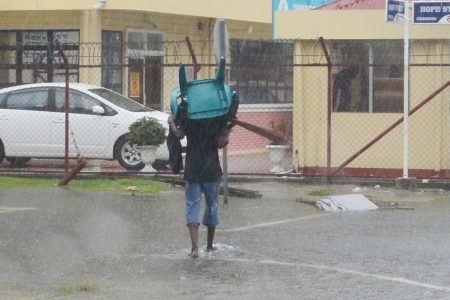 A man uses a chair to shield himself from the rain (Orlando Charles photo) 