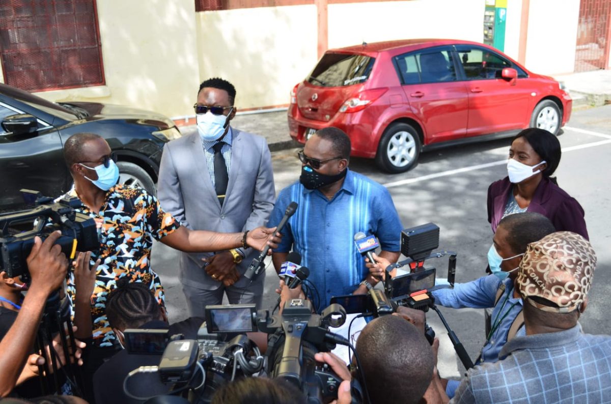 Roysdale Forde (centre) speaking to reporters today about the court filing. Christopher Jones is standing next to him. (Orlando Charles photo)