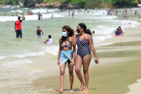 Two beach-goers stroll along Maracas Beach taking precaution by wearing masks. -Photo: ISHMAEL SALANDY