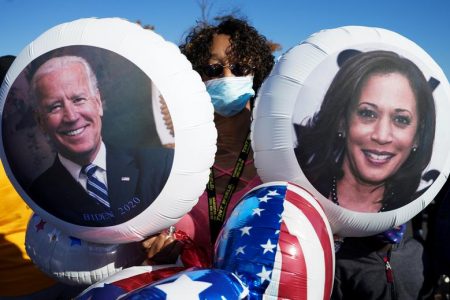A supporter of Joe Biden holds balloons with the faces of Joe Biden and Kamala Harris as she celebrates near the site of a planned election victory celebration in Wilmington, Delaware, November 7.  REUTERS/Kevin Lamarque