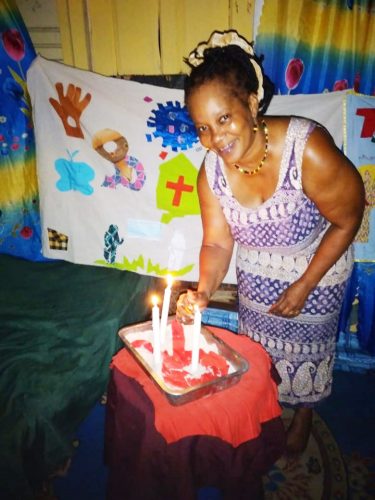 Marlyn Cameron lighting candles in remembrance of persons who have died from HIV/AIDS. Behind her is the quilt highlighting messages of prevention. 