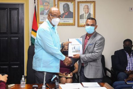 Public Works Minister Juan Edghill (left) receiving the report on the investigation into the Demerara Harbour Bridge Asphalt’s Plant from Chateram Ramdihal, who headed the investigative team.
