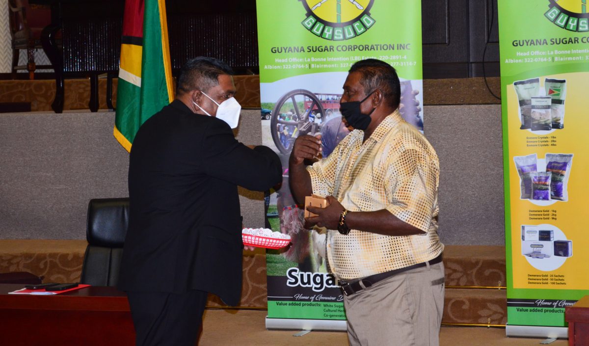 Minister of Agriculture Zulfikar Mustapha (left) presenting an award to one of the workers who has worked more than 40 years at the sugar company. (Orlando Charles photo)