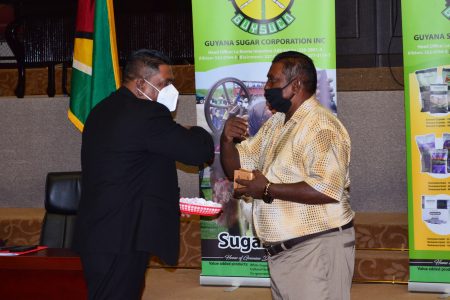 Minister of Agriculture Zulfikar Mustapha (left) presenting an award to one of the workers who has worked more than 40 years at the sugar company. (Orlando Charles photo)