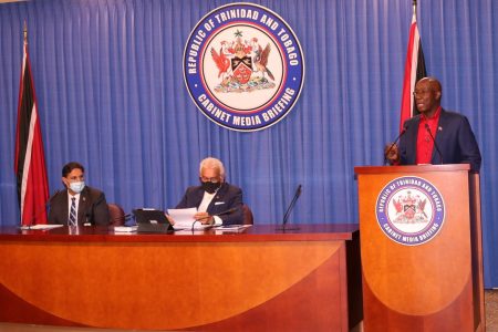 Prime Minister Dr Keith Rowley addresses the media during yesterday’s COVID-19 briefing at the Diplomatic Centre, Port-of-Spain. Also in the picture are Chief Medical Officer Dr Roshan Parasram and Health Minister Terrence Deyalsingh.