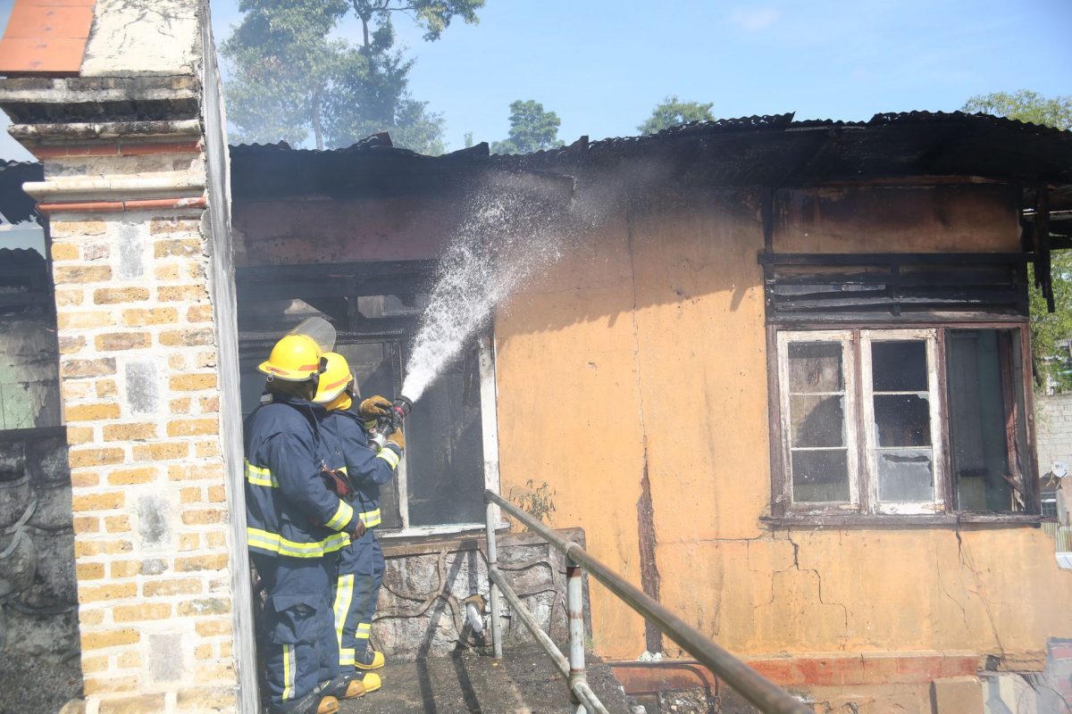 Firefighters douse one of the houses destroyed by fire on Calvary Hill, Port-of-Spain, yesterday. 