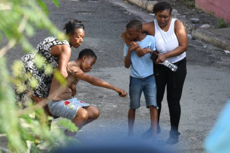 The mother of Rushane Thomas being consoled as she mourned her son’s death yesterday. He was reportedly killed in a police shootout in the Alli Lane gully off Slipe Pen Road in Kingston.