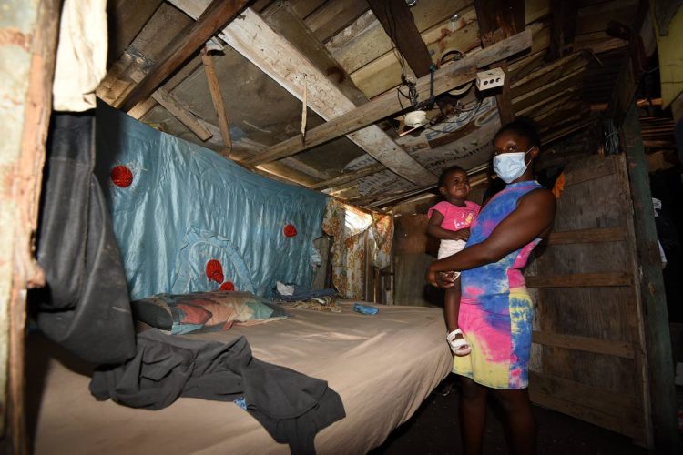 Two-year-old Alia Lindsay cries in the arms of her mother, Natasha Jones, inside the three-room shack she shared with her seven children before five were taken into state care. Jones is seeking help to build a proper house so she can get back her children.
