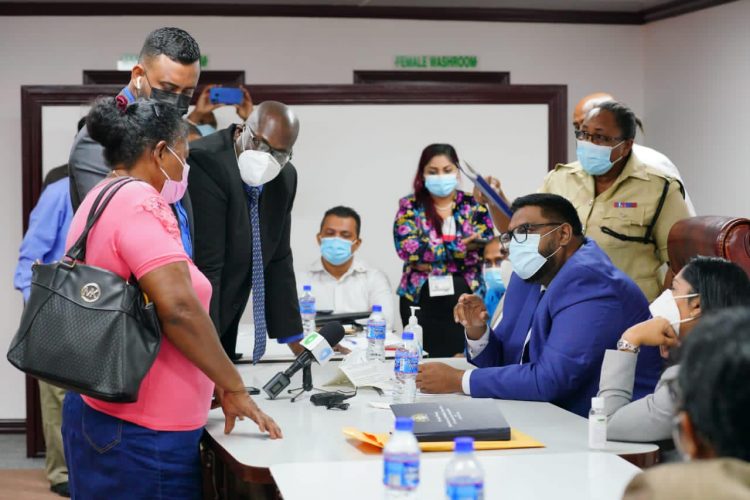 President Irfaan Ali (seated at right) listening to a member of the public. (Office of the President photo) 