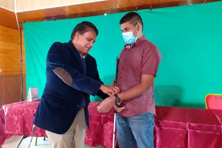 Oropouche East MP Dr Roodal Moonilal presents Debe High Secondary School’s visually impaired student Ryan Khamram with a Five Senses smart watch for his success at CXC exams.