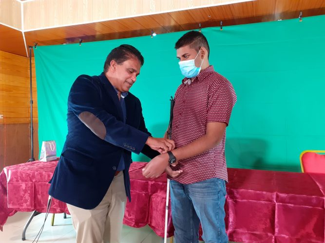 Oropouche East MP Dr Roodal Moonilal presents Debe High Secondary School’s visually impaired student Ryan Khamram with a Five Senses smart watch for his success at CXC exams.