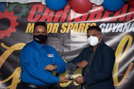 Minister within the Ministry of Public Work Deodat Indar (at right) presenting a token and certificate to the best Employee at Caribbean Motor Spares yesterday (DPI photo)