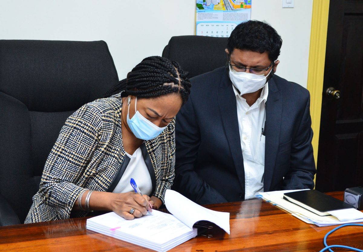 General Manager of the Transport and Har-bours Department, Marclene Merchant (right) signs the contract for the project yesterday in the presence of Permanent Secretary of the Ministry of Public Works, Vladim Persaud. (Orlando Charles photo) 