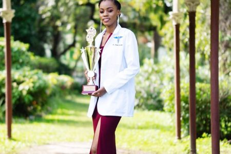 Dr Jonelle Europe strikes a pose with the trophy she received for topping her class