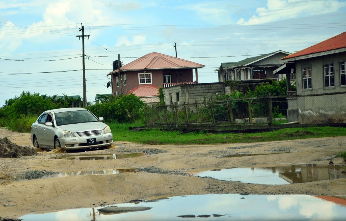 A car braving the potholes in Block “V” Herstelling road (Photo by Orlando Charles)