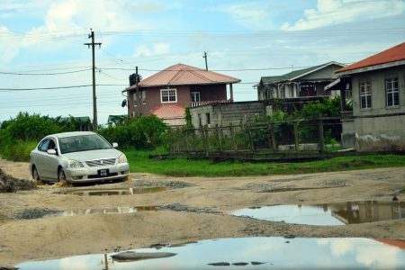 A car braving the potholes in Block “V” Herstelling road (Photo by Orlando Charles)