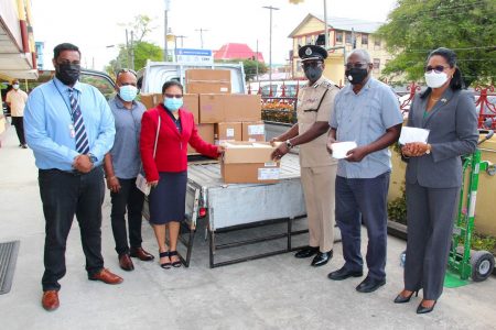 The Giftland Team (left) handing over the masks to the Police Commissioner, Nigel Hoppie (third from right), Minister of Home Affairs Robeson Benn & Permanent Secretary Mae Thomas. 