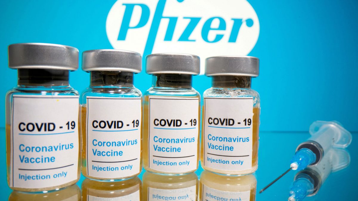 FILE PHOTO: Vials with a sticker reading, "COVID-19 / Coronavirus vaccine / Injection only" and a medical syringe are seen in front of a displayed Pfizer logo in this illustration taken October 31, 2020. REUTERS/Dado Ruvic/Illustration/File Photo