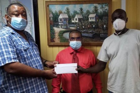 Uborn France (right) hands over sponsorship to BCB President Hilbert Foster while Region 6 REO Navindra Persaud looks on. 