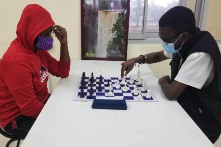Junior campion, Keron Sandiford (in red) and his senior counterpart, Davion Mars during the National Blitz Chess Championship on Old Year’s Day.
