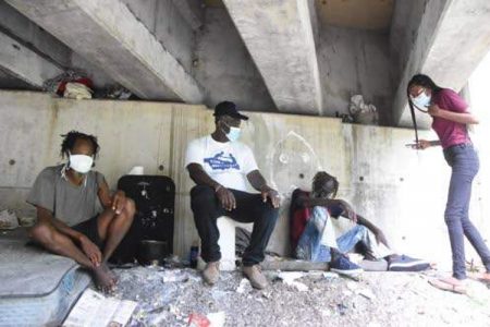 Public health inspector and Icons of Annotto Bay executive Khaleen Edwards (right) sees for herself the condition under which Daniel Stewart (left) and Nicholas Rowe (second right) are living. At second left is Icons founder and President Wyatt “Spur” Williams.