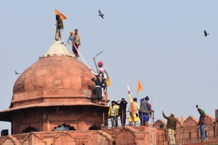 Sikhs hoist a Nishan Sahib, a Sikh religious flag, on a minaret of the historic Red Fort monument in New Delhi, India, Tuesday, Jan. 26, 2021. Tens of thousands of protesting farmers drove long lines of tractors into India’s capital on Tuesday, breaking through police barricades, defying tear gas and storming the historic Red Fort as the nation celebrated Republic Day. (AP Photo/Dinesh Joshi)(ASSOCIATED PRESS)